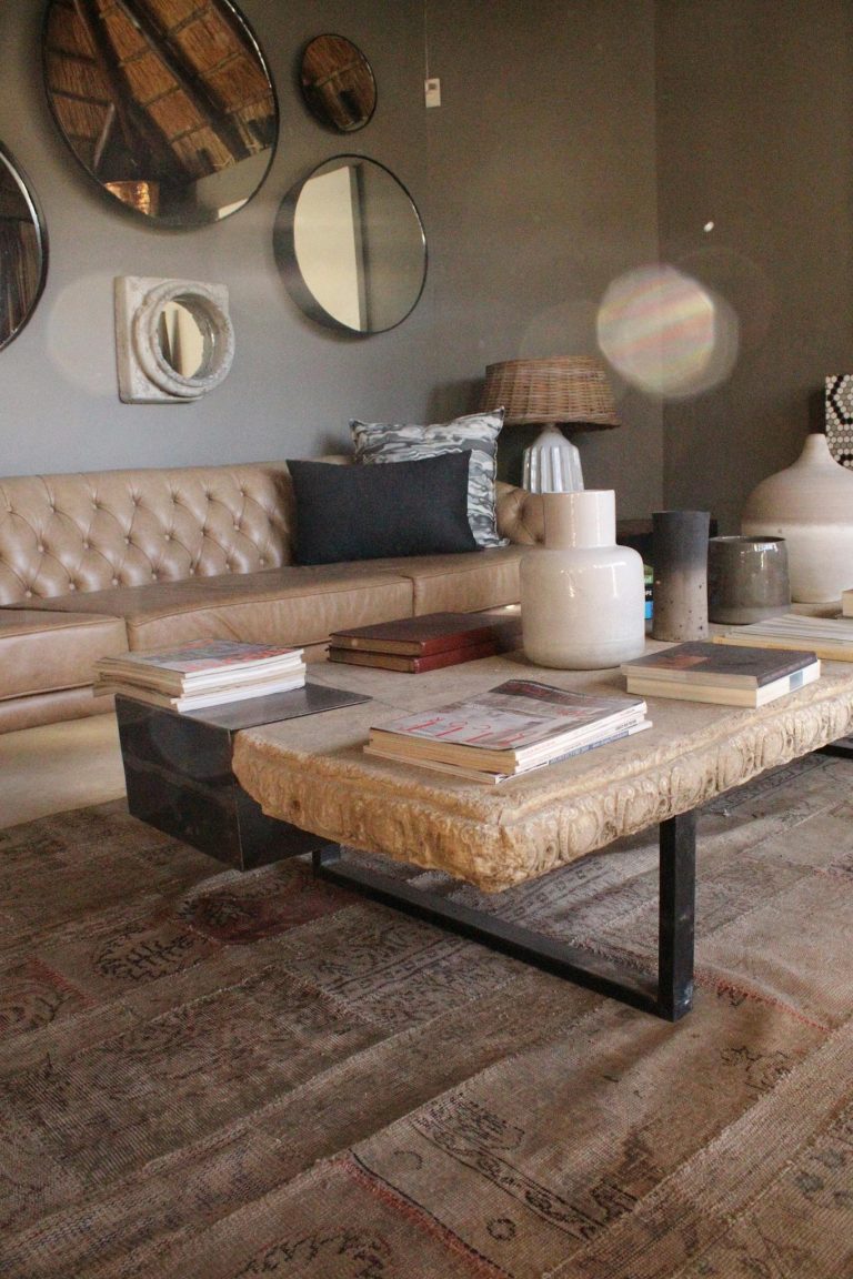 Contemporary living room featuring a sofa, center table, books, and decorative mirrors.